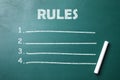 White chalk stick on greenboard and list of rules Royalty Free Stock Photo