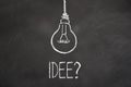 Chalk text `Idee` and lightbulb on chalkboard. Translation: `Idea` Royalty Free Stock Photo