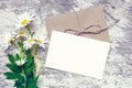 White chamomile flowers and blank white greeting card with envelope