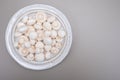 White champignon mushrooms fresh uncooked on white ceramic plate copy space