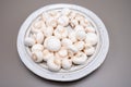 White champignon mushrooms fresh uncooked on white ceramic plate copy space