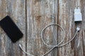 White charger and black smartphone on old wooden background. Information technology horizontal digital photo. Modern layout on