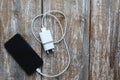 White charger and black smartphone on old wooden background. Information technology horizontal digital photo. Modern layout on