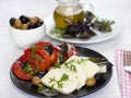 White cheese with tomatoes, green and black olives, basil, coriander and olive oil on a black plate Royalty Free Stock Photo