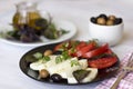 White cheese with tomatoes, green and black olives, basil, coriander and olive oil on a black plate Royalty Free Stock Photo