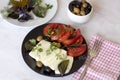 White cheese with tomatoes, green and black olives, basil, coriander and olive oil on a black plate Royalty Free Stock Photo