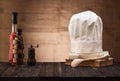 White chef`s hat and old cookbook on the kitchen table, wooden spoon and spices. Royalty Free Stock Photo