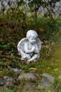 White cherub angel sitting in garden praying