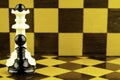 The white chess king and black pawn stand next to a chessboard copy space Royalty Free Stock Photo