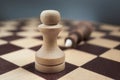 White chess pawn defeated black king. The concept of never giving up. Background in blur Royalty Free Stock Photo