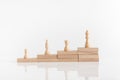 White chess pieces on a stepped stack of wooden blocks with queen piece