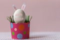 White chicken egg with bunny ears in an eco-friendly pink paper tray, box. Happy Easter holiday concept. English text Happy Easter Royalty Free Stock Photo