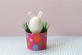 White chicken egg with bunny ears in an eco-friendly pink paper tray, box. Happy Easter holiday concept