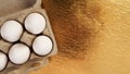 White chicken eggs in a cardboard tray on a gold background Royalty Free Stock Photo