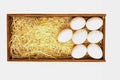 White chicken eggs lie on straw in a wooden box, isolated on a white background Royalty Free Stock Photo