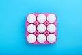 White chicken eggs in a pink carton tray box on blue background with copy space Royalty Free Stock Photo