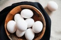White chicken eggs in a wooden bowl on a dark towel Royalty Free Stock Photo