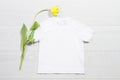 White children t-shirt mockup. Template blank kids shirt top view. White wooden background. Mother women day holiday. Yellow tulip