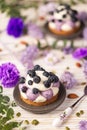 White chocolate and blueberry sable tartelette with vintage spoon on a white drift wood table with purple dry flowers background. Royalty Free Stock Photo