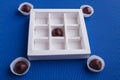 White chocolate box with brown candies on blue background.