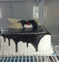 White and chocolate decorated birthday cake placed in the refrigerator