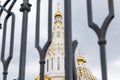 White christian church with gilded domes seen through defocused black wrought fence