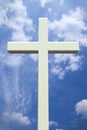 White Christian cross in front of a cloudy sky