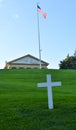 White Christian Cross surrounded by green grass with American fl Royalty Free Stock Photo