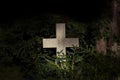 White christian granite cross in a dark mysterious forest with green foliage with copy space. Symbol for christianity, resurrectio