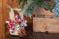 White Christmas candle holder decorated with pine cone and ashberry stick under Christmas tree on wooden table. Royalty Free Stock Photo