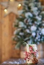 White Christmas candle holder decorated with pine cone and ashberry stick under Christmas tree on wooden table. Royalty Free Stock Photo