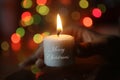 White Christmas candle light in hand. On beautiful background of colorful bokeh lights decoration. Royalty Free Stock Photo