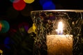 White Christmas Candle Surrounded by Christmas Lights and Evergreen Branches
