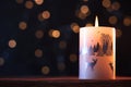 White Christmas candle on a wooden table with garlands background and winter themes