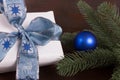 White Christmas gift with blue christmas ball on dark wooden background