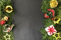 Christmas gift box and Christmas decorations on arborvitae branches placed on black background.