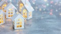 White christmas lights in form of toy wooden houses on silver background