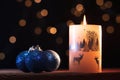 White Christmas candle and blue shiny Christmas balls with garlands light in the background