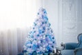 A white Christmas tree decorated with balls and ribbons stands in the room. Beautiful New Year`s interior Royalty Free Stock Photo