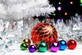 White christmas tree standing in the sparkling tinsel with christmas decorations on dark background with blurred lights Royalty Free Stock Photo