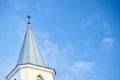 White church steeple with cross with window blind and cross over blue sky background. Religious easter background with Royalty Free Stock Photo