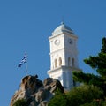 White church tower and greek flag against blue sky Royalty Free Stock Photo