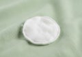 A white, circular fabric patch rests on a light green textile surface. Royalty Free Stock Photo