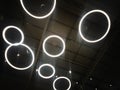 White circular ring shaped lamps hang under a concrete ceiling Royalty Free Stock Photo