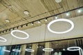 White circular ring shaped lamps hang under concrete ceiling with external wiring and black fixtures, with mirror Royalty Free Stock Photo