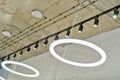 White circular ring shaped lamps hang under concrete ceiling with external wiring and black fixtures Royalty Free Stock Photo