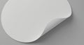 A white circular sheet with a curled-up corner rests on a smooth gray surface. The Royalty Free Stock Photo
