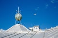 A white cladded roof with a wind indicator on the roof on a sunny day