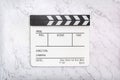 White clapboard on white marble background. Flat lay of clapper board on natural marble texture
