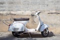 White Classic Vespa scooter stands parked near the concrete old